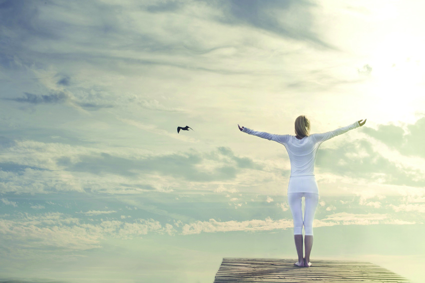 woman with open arms meditating in front of a spectacular sky woman with open arms meditating in front of a spectacular sky